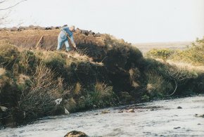 man cutting a turf bank beside the clady river coshclady between gweedore and bunbeg county Donegal
